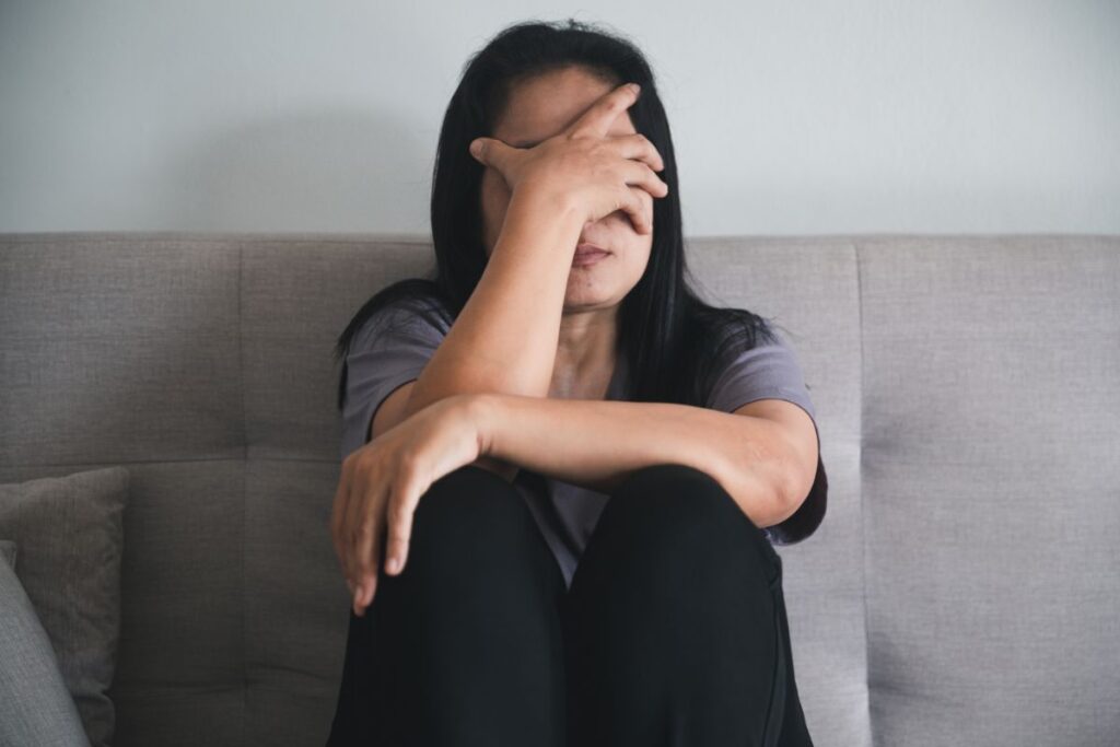 A woman with a mental health disorder sitting with her head in her hands