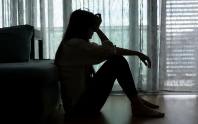 A person with depression holding their heads in their hands