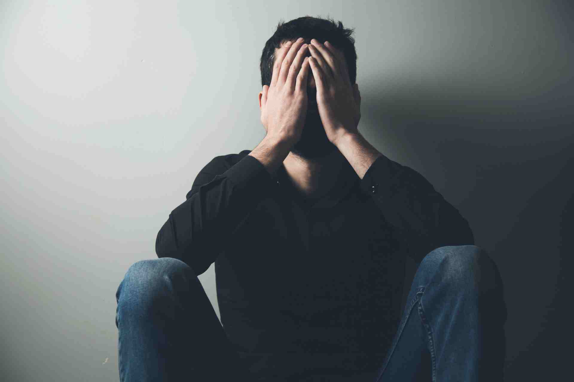 Man sitting with hands covering face showing emotional distress related to anxiety