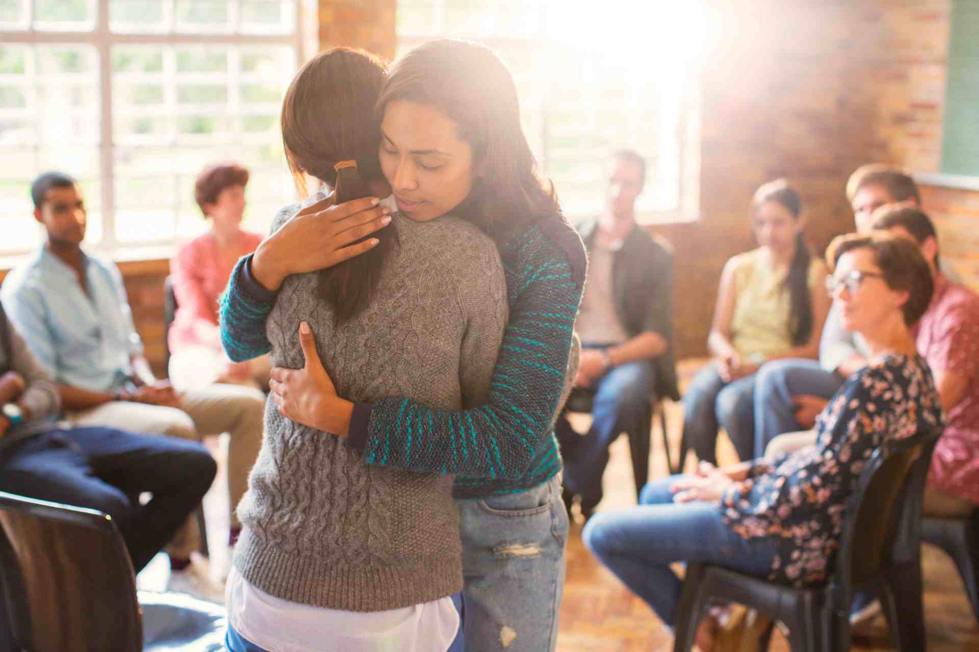 Two participants hugging during a mental health support group session