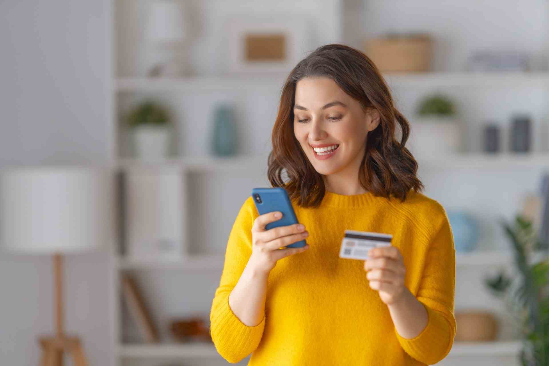 Woman using her phone and holding a credit card while reviewing outpatient mental health payment options